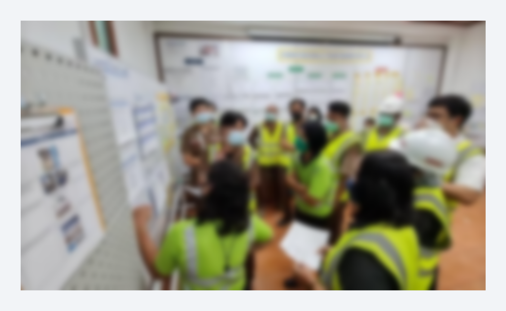 Cross-functional team gathered around a visual management board 